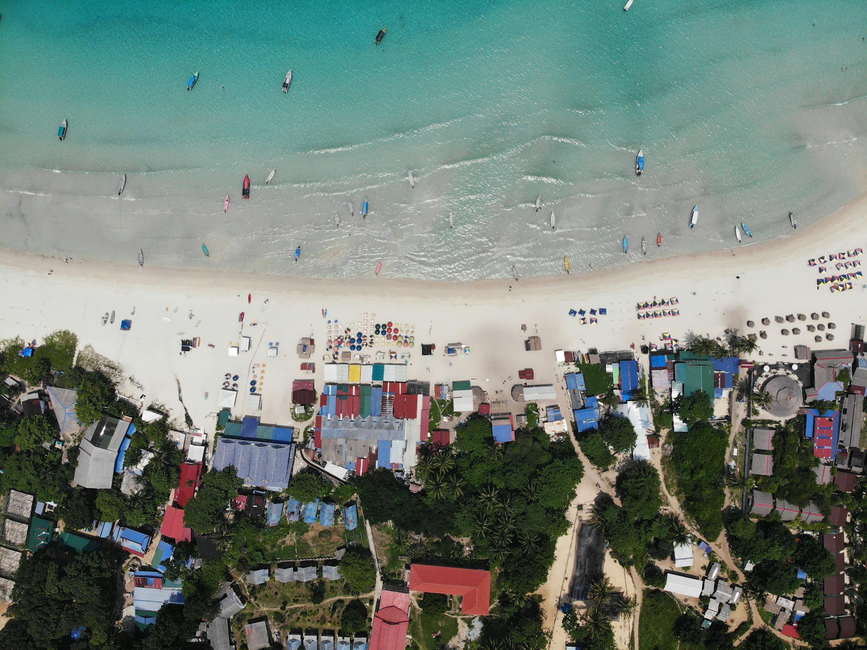 Stunning aerial view of Pulau Perhentian Kecil's vibrant beachfront with colorful buildings and serene waters.