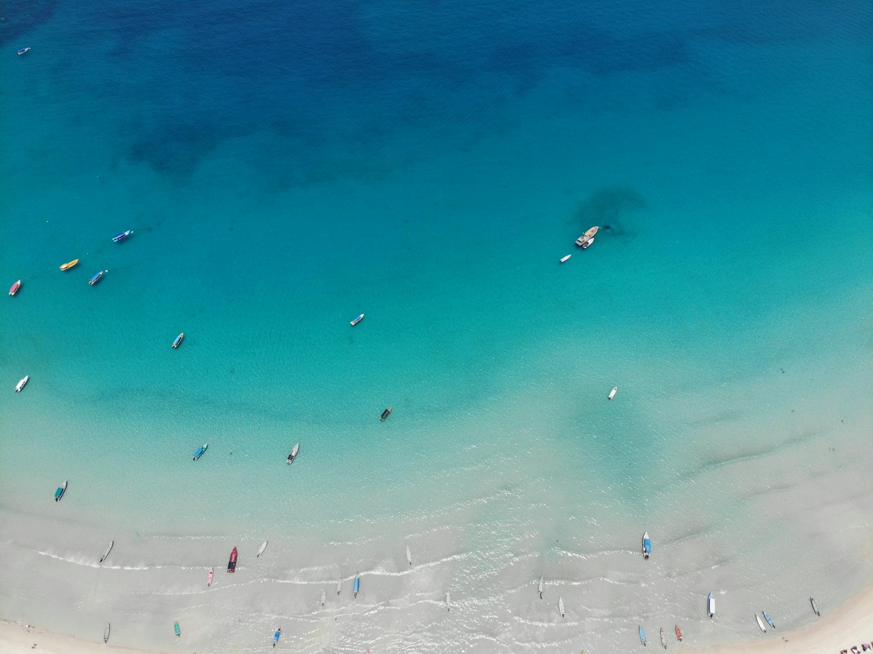 Drone view of various vessels floating on clear turquoise seawater in tropical resort on sunny summer day in coastal area