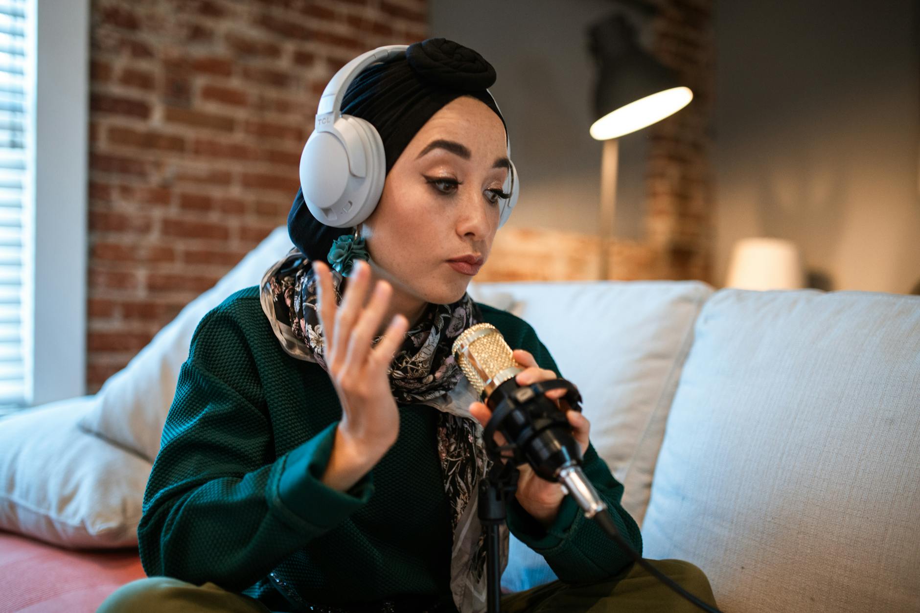 Young woman podcasting with headphones and a microphone indoors.