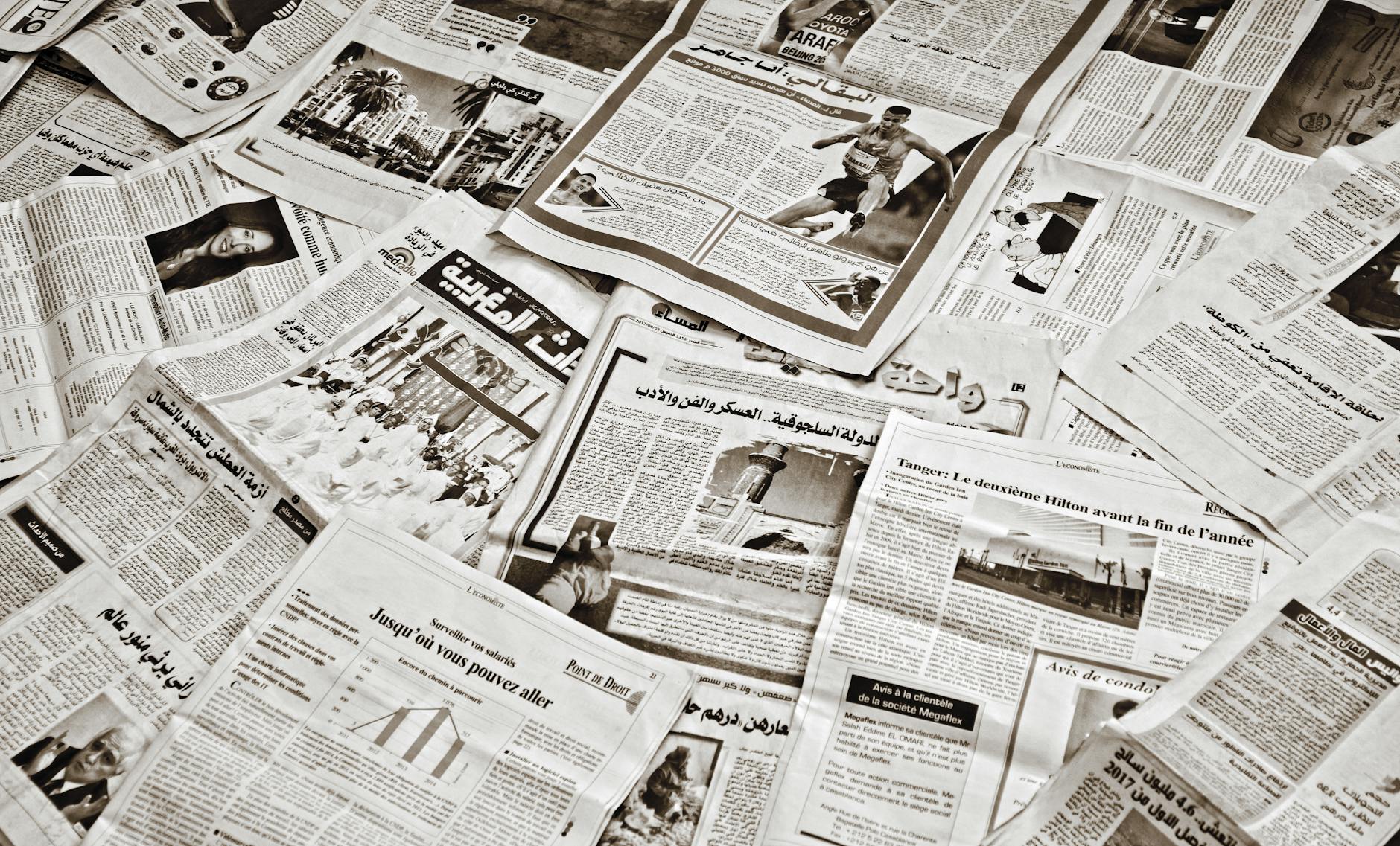 A collection of Arabic newspapers spread across a surface, showcasing diverse headlines and articles.