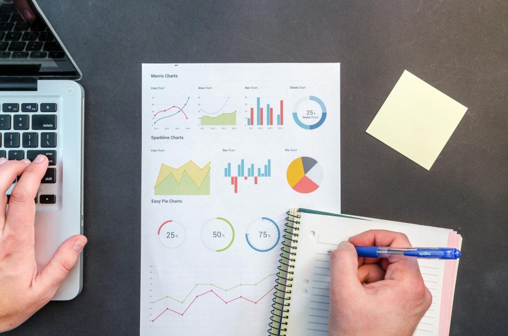 Hands interacting with charts and notes for data analysis on a desk.
