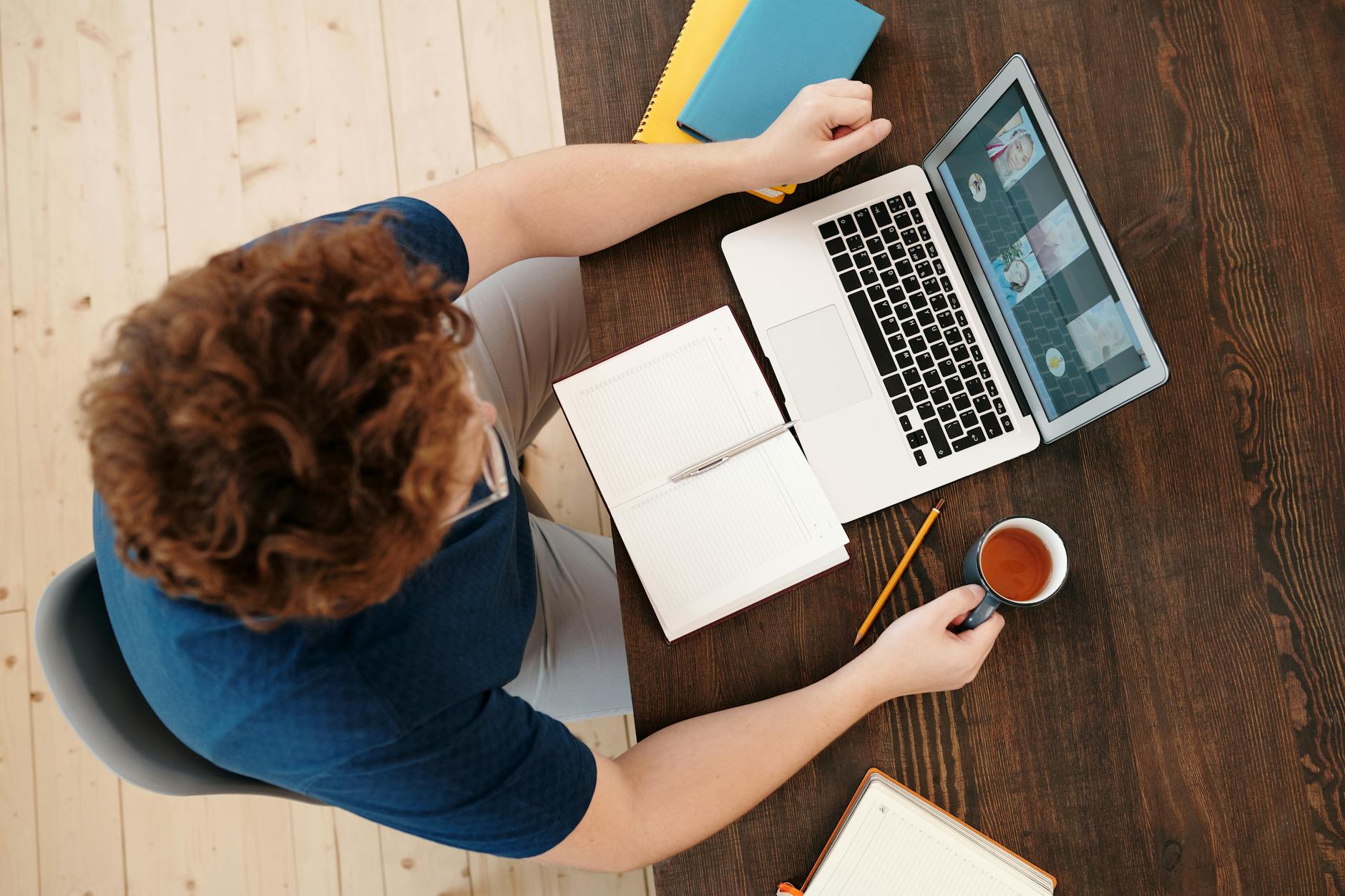 Man working on a laptop at home with a notebook and coffee, perfect for remote work themes.