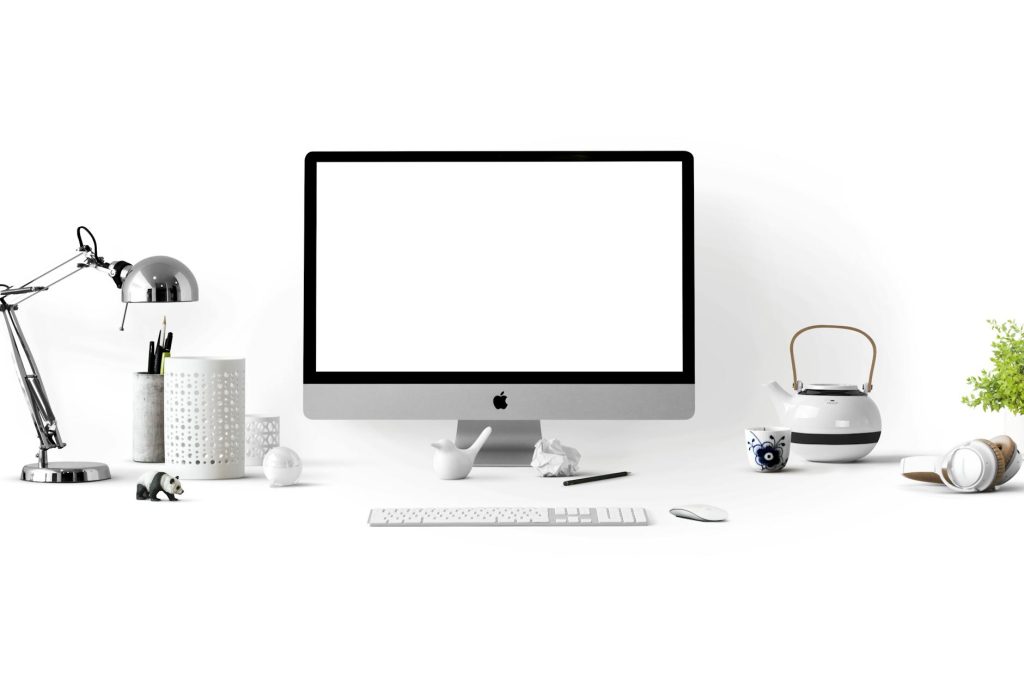 Minimalist office desk with an iMac, lamp, and stationary, perfect for tech backgrounds.