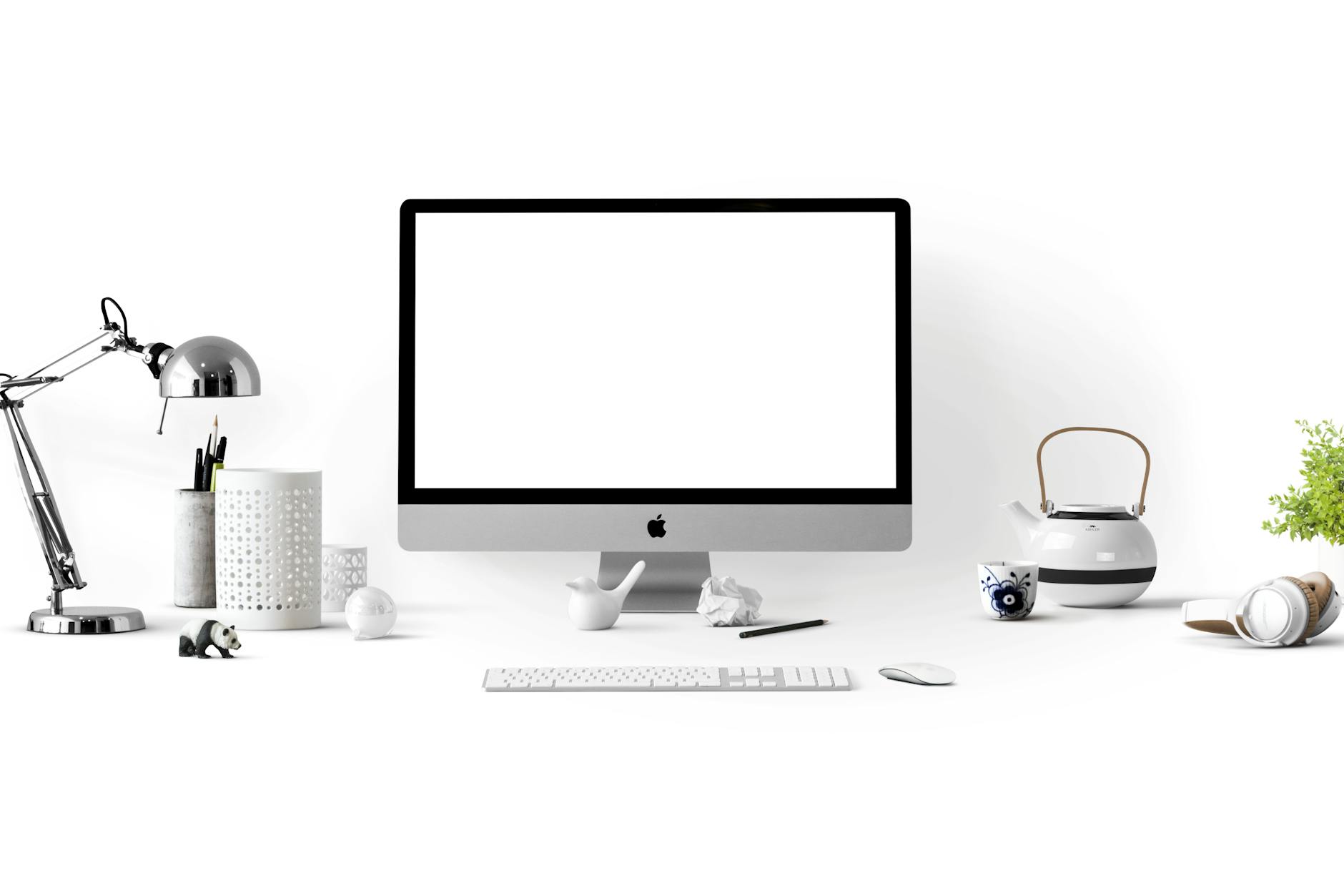 Minimalist office desk with an iMac, lamp, and stationary, perfect for tech backgrounds.