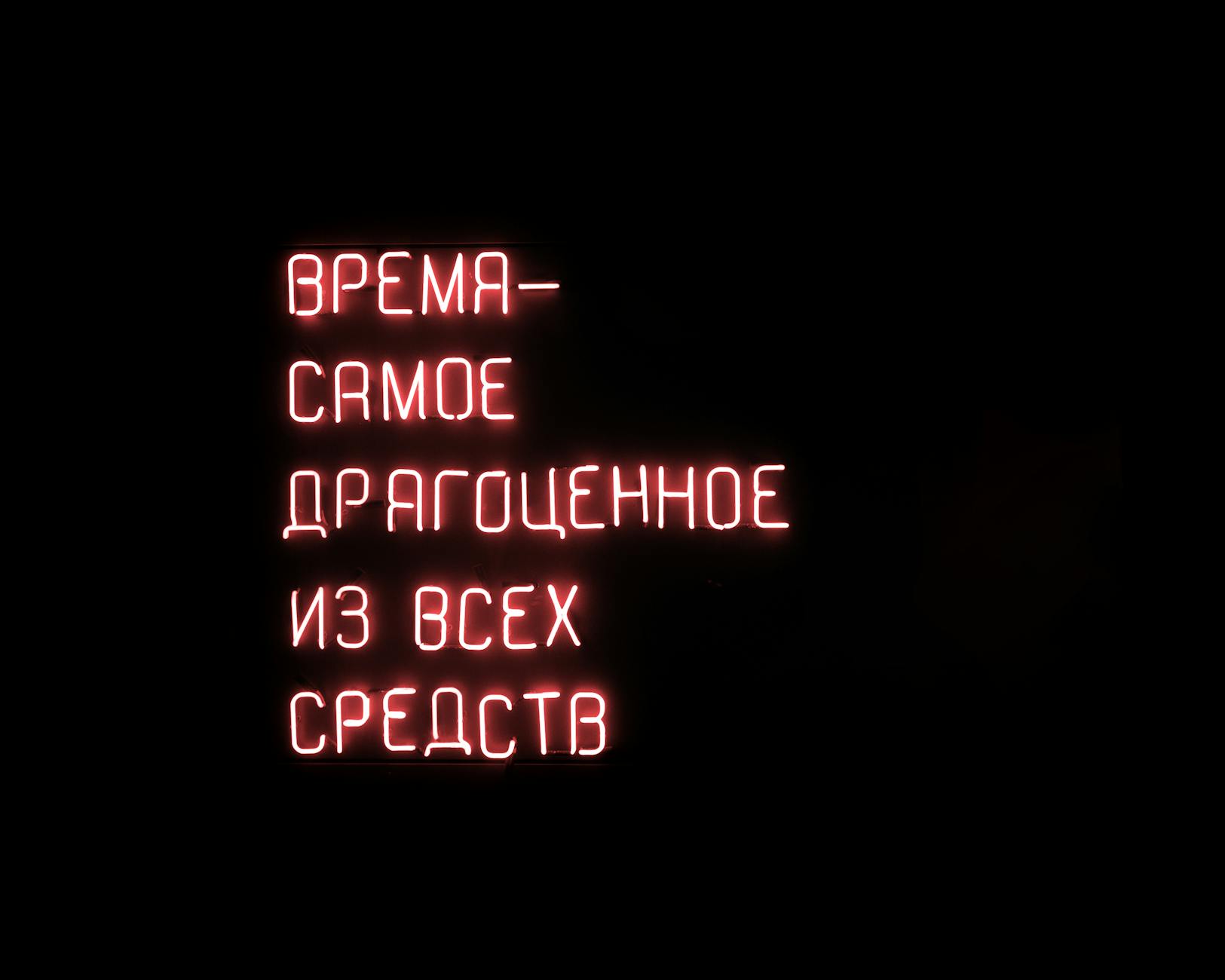 Glowing red neon sign with a motivational Russian text on a dark background.
