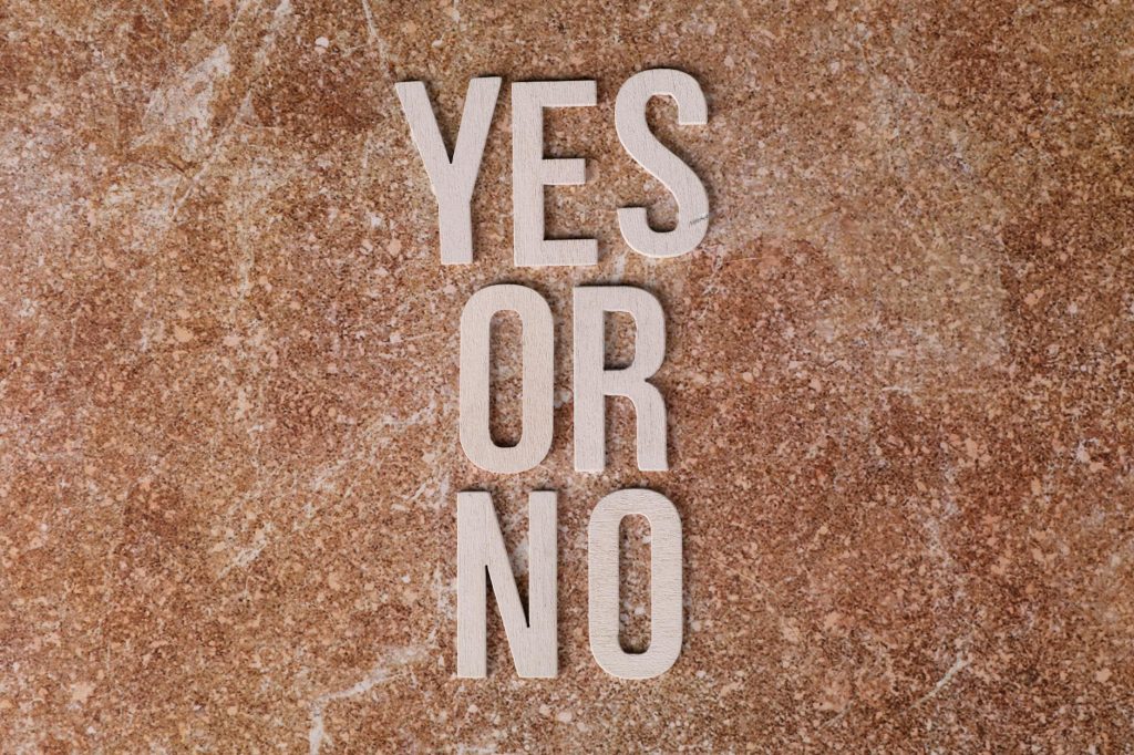 Wooden letters on marble background spell 'YES OR NO' symbolizing choices.