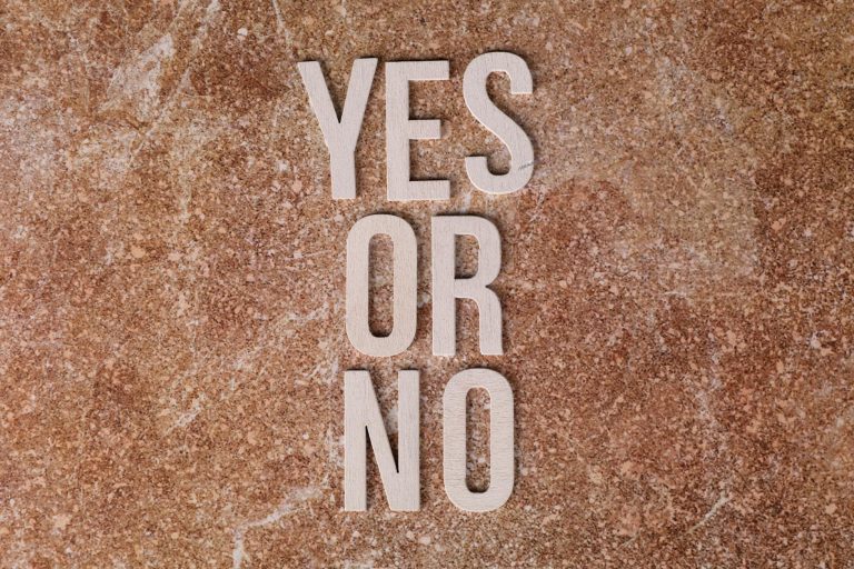 Wooden letters on marble background spell 'YES OR NO' symbolizing choices.