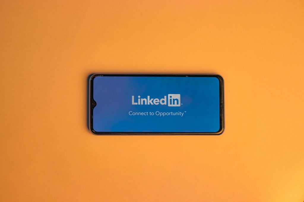 Smartphone showing LinkedIn login on vibrant orange background, symbolizing connectivity.