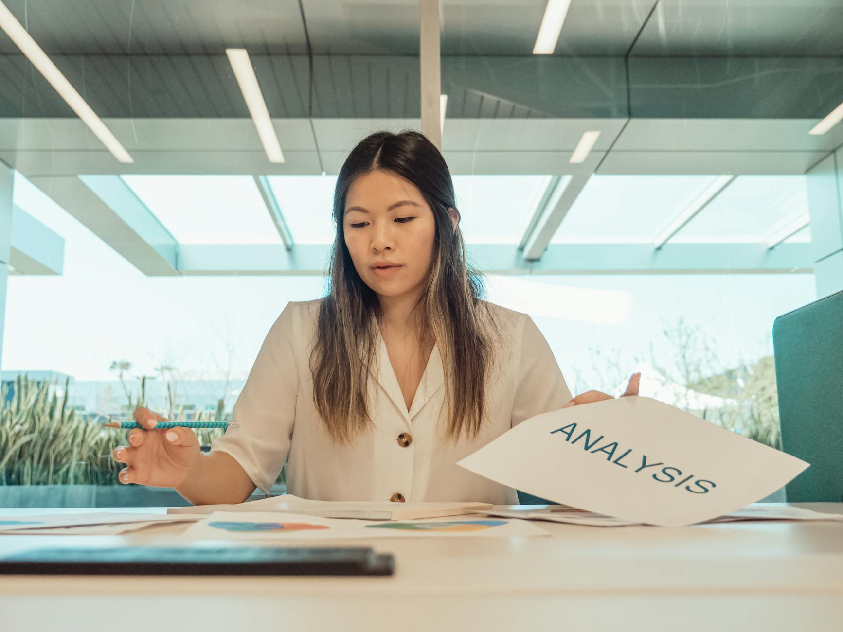 Professional woman in office reviewing analysis documents at desk.