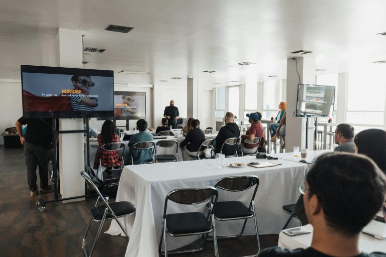 Speaker presenting to a diverse audience at a modern indoor conference setting.