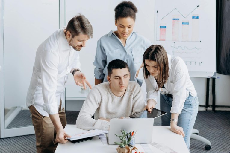 A diverse group of colleagues working together on a business project in an office setting.