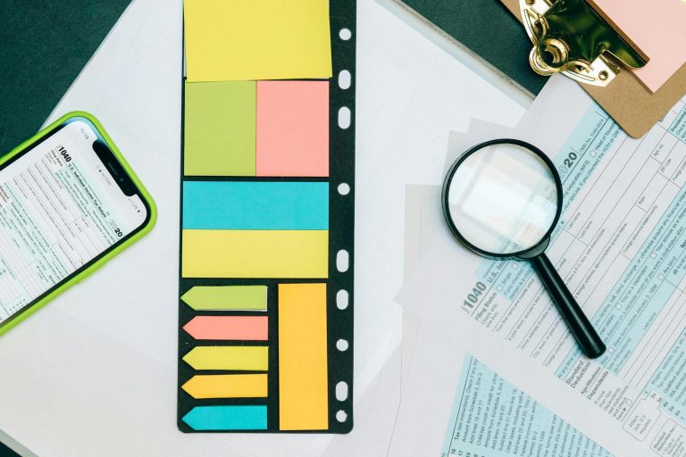 Colorful office supplies with smartphone and magnifying glass on tax forms. Perfect for business and financial themes.