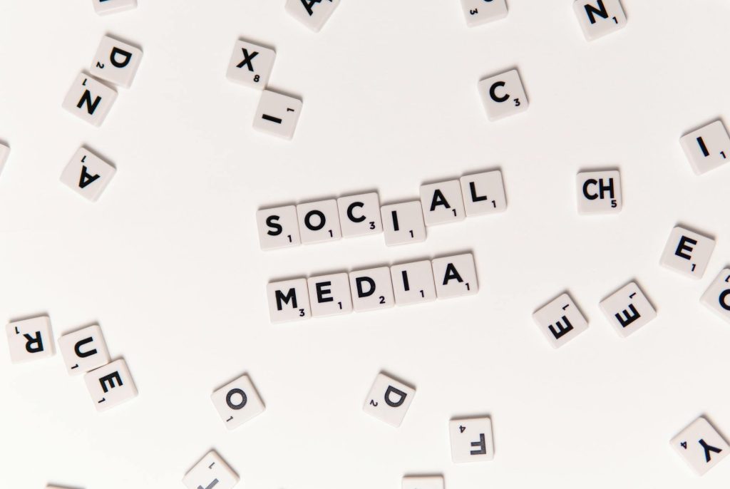 Flat lay of letter tiles spelling Social Media with scattered white tiles on a surface.