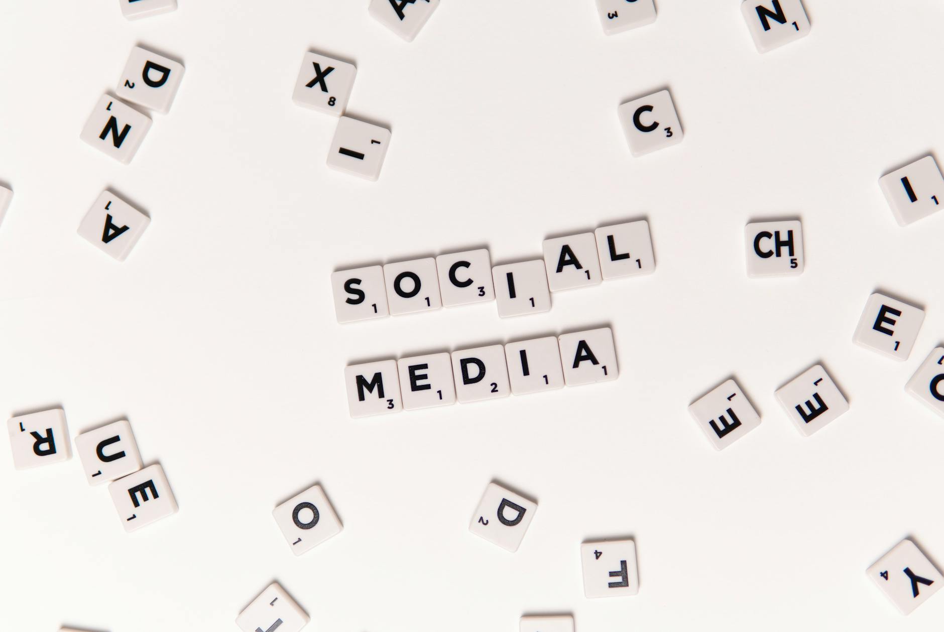 Flat lay of letter tiles spelling Social Media with scattered white tiles on a surface.