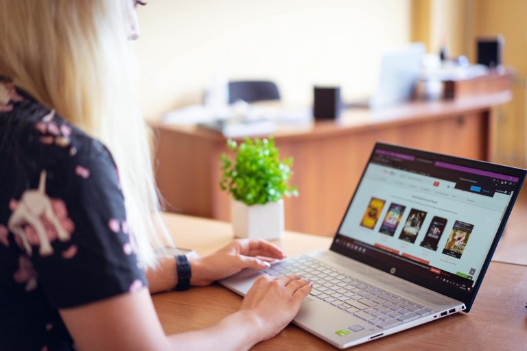 A woman browsing an online store on a laptop in a modern home office setting.