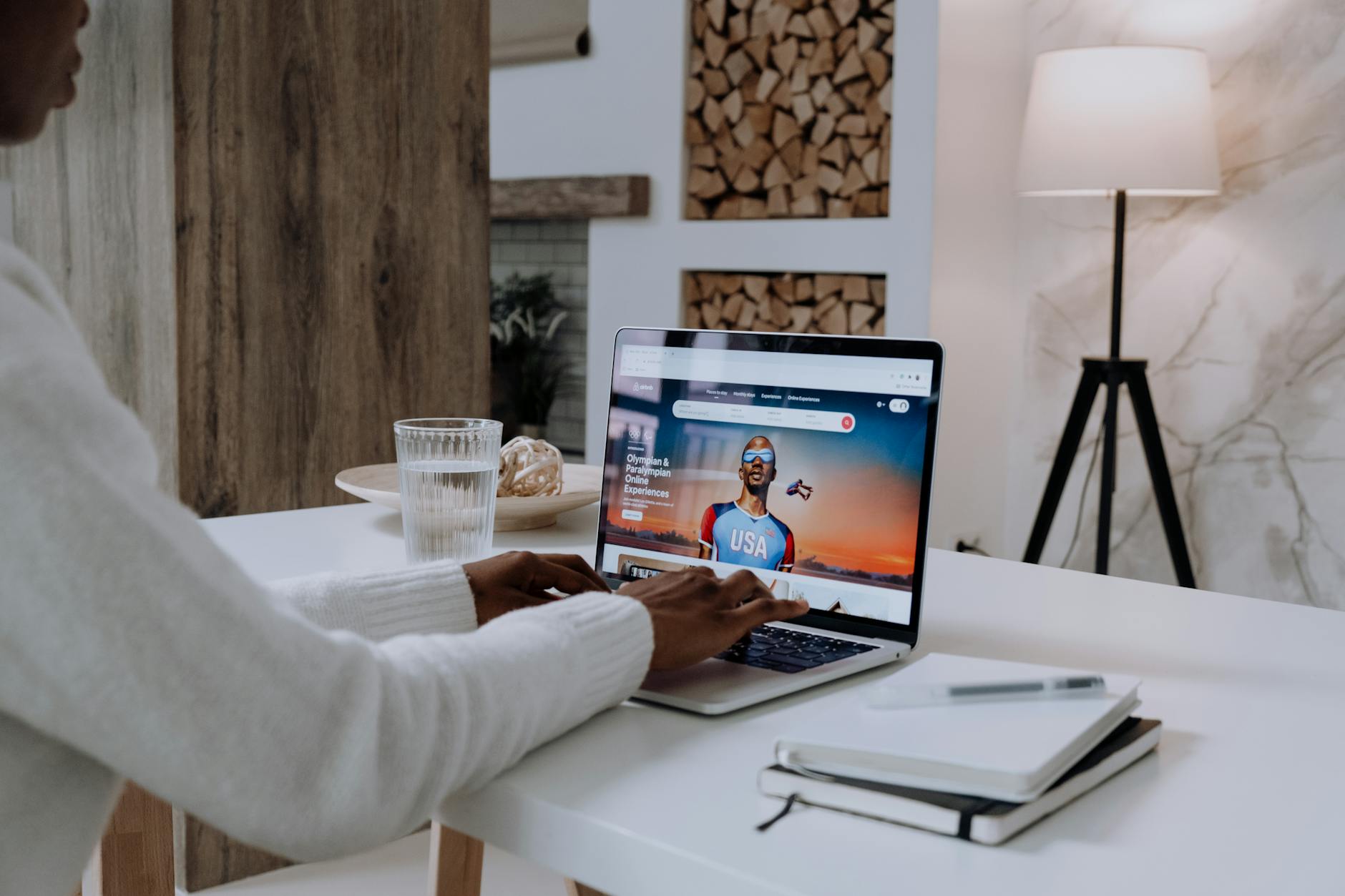 Faceless person using a laptop with online content in a cozy modern setting.