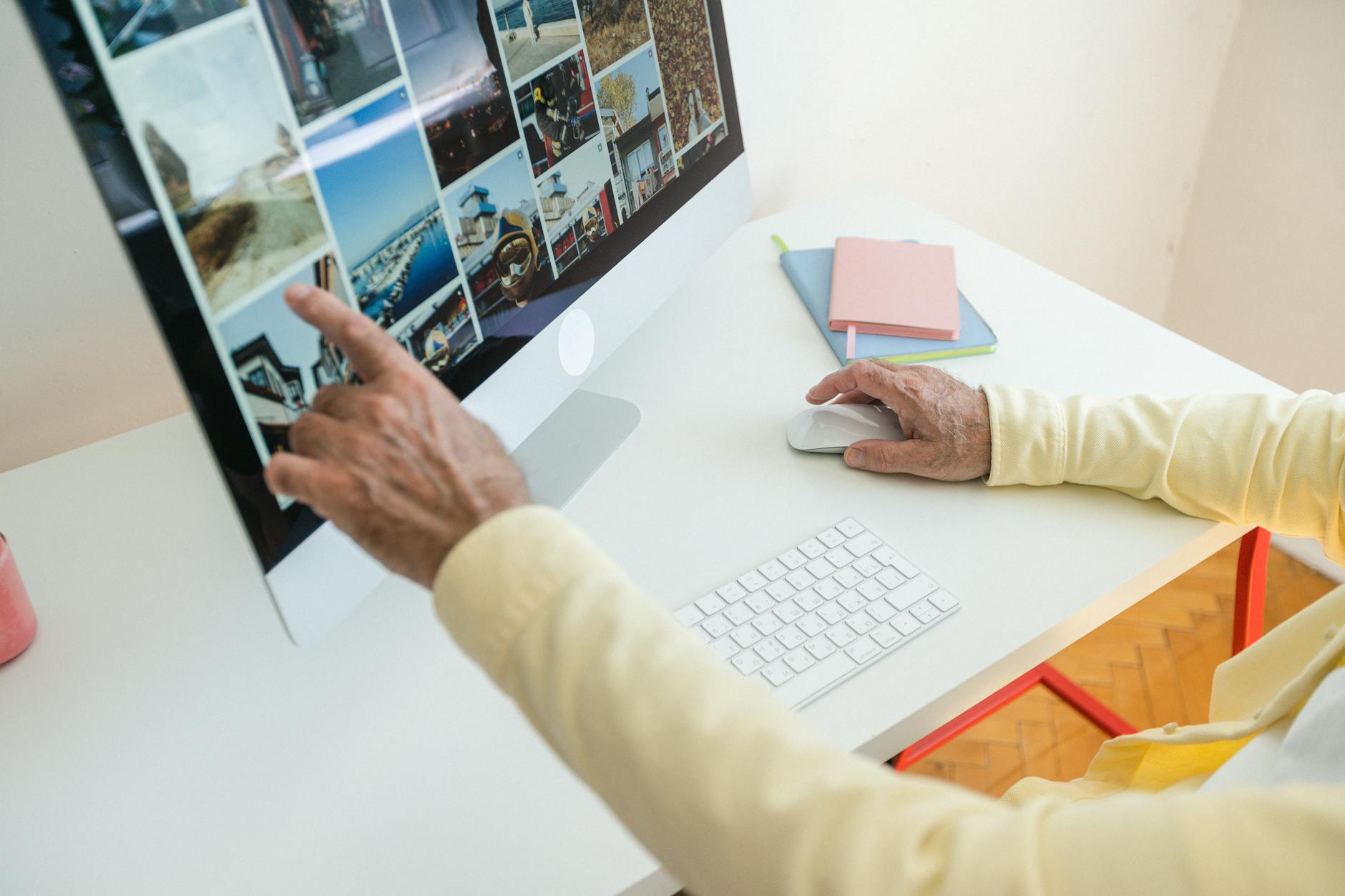 Senior adult browsing photos on a desktop computer in a modern indoor setting.